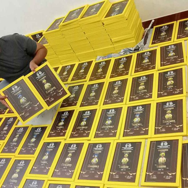 Professional worker showcasing a high-quality yellow graduation frame for bulk order.